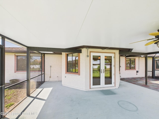 unfurnished sunroom with a ceiling fan, a healthy amount of sunlight, and french doors