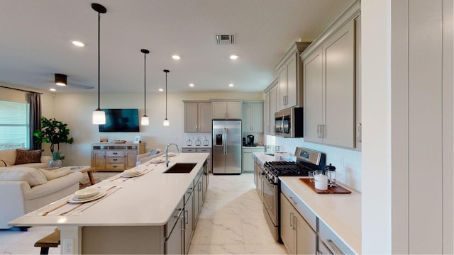 kitchen with a sink, marble finish floor, open floor plan, gray cabinetry, and appliances with stainless steel finishes