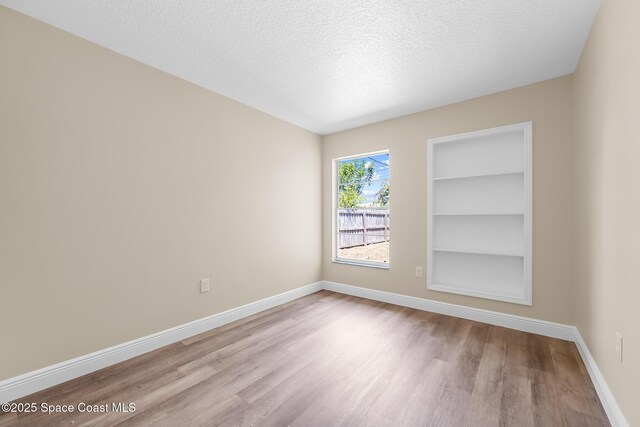 619 Dinner St NE, Palm Bay, FL 32907 - spare room with a textured ceiling, wood finished floors, baseboards, and built in shelves