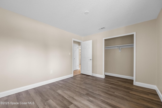 619 Dinner St NE, Palm Bay, FL 32907 - unfurnished bedroom with a closet, a textured ceiling, visible vents, dark wood-style flooring, and baseboards