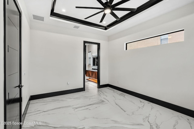 spare room featuring visible vents, baseboards, a raised ceiling, ceiling fan, and marble finish floor