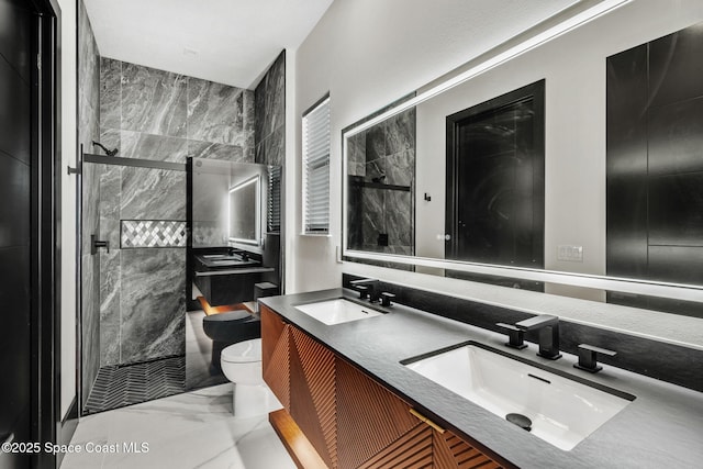 full bath with toilet, marble finish floor, a sink, and a stall shower