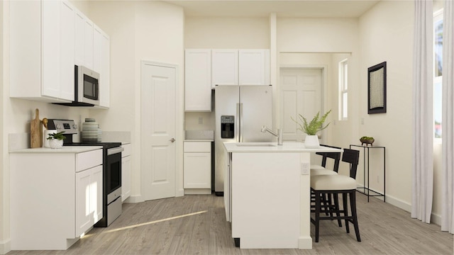 kitchen with a kitchen breakfast bar, white cabinetry, light wood-type flooring, and appliances with stainless steel finishes