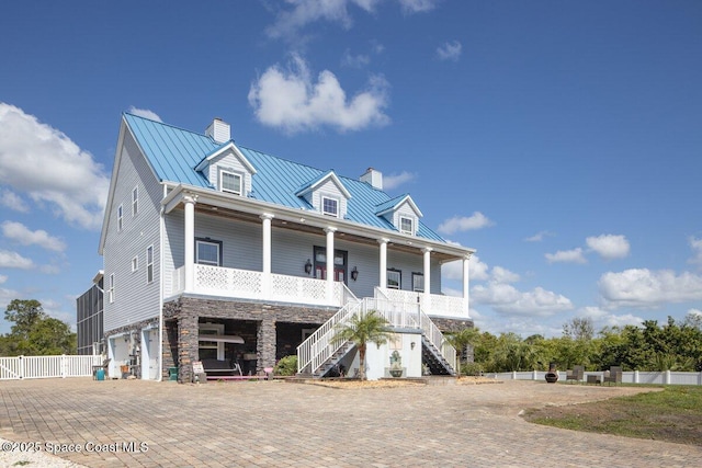 3824 Luxury Ln, Titusville, FL 32796 - raised beach house featuring a chimney, covered porch, a standing seam roof, stairway, and a garage