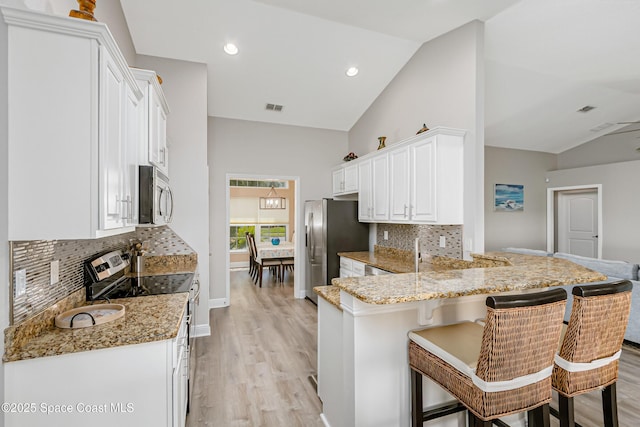 4569 Lady Hawk Way, Melbourne, FL 32904 - kitchen featuring appliances with stainless steel finishes, vaulted ceiling, a peninsula, light wood-style floors, and a kitchen breakfast bar