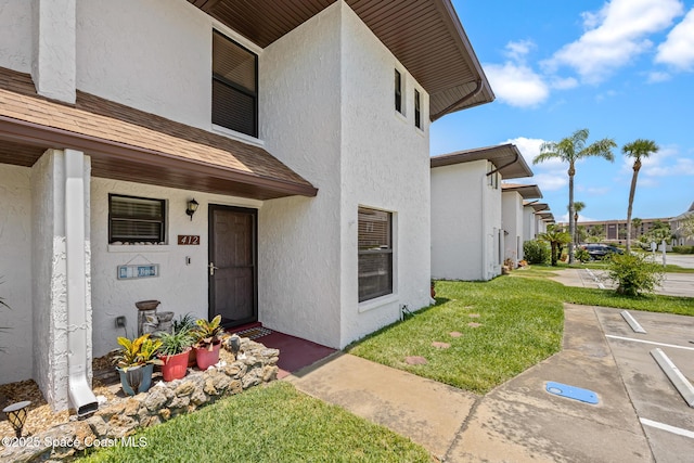 412 Sailfish Ave Unit 16, Cape Canaveral, FL 32920 - entrance to property with stucco siding, a lawn, and roof with shingles
