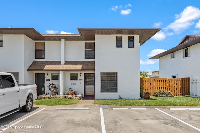 412 Sailfish Ave Unit 16, Cape Canaveral, FL 32920 - view of front of house with fence, uncovered parking, stucco siding, and a shingled roof