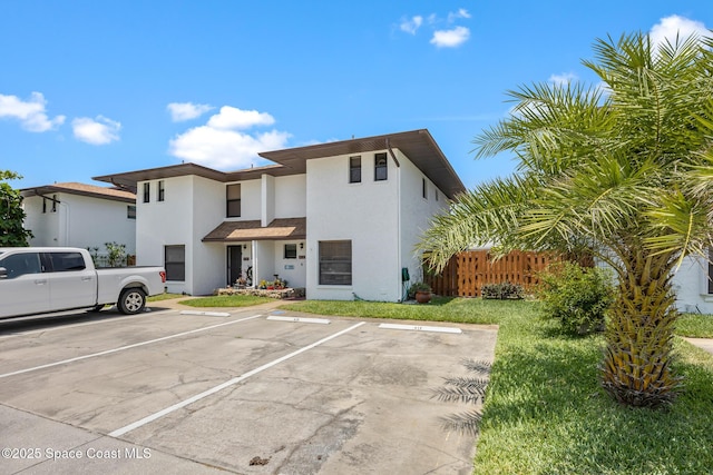 412 Sailfish Ave Unit 16, Cape Canaveral, FL 32920 - view of front of property featuring uncovered parking, stucco siding, and fence
