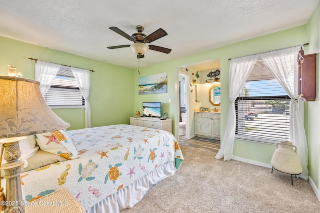 412 Sailfish Ave Unit 16, Cape Canaveral, FL 32920 - carpeted bedroom with multiple windows, a textured ceiling, ceiling fan, baseboards, and ensuite bath