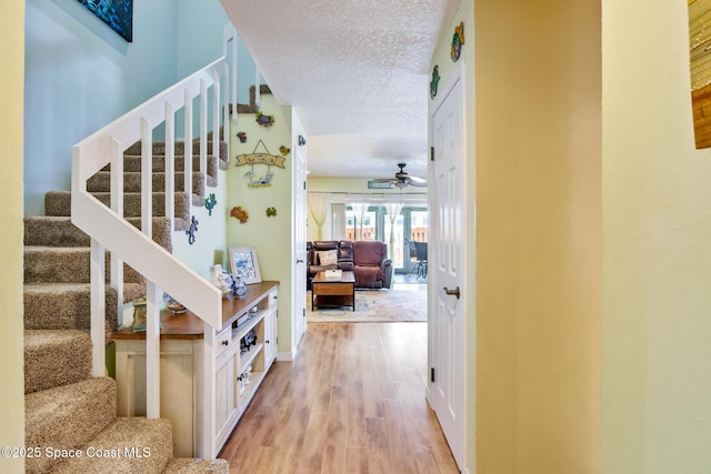 412 Sailfish Ave Unit 16, Cape Canaveral, FL 32920 - hallway featuring light wood-type flooring, stairway, a textured ceiling, and baseboards