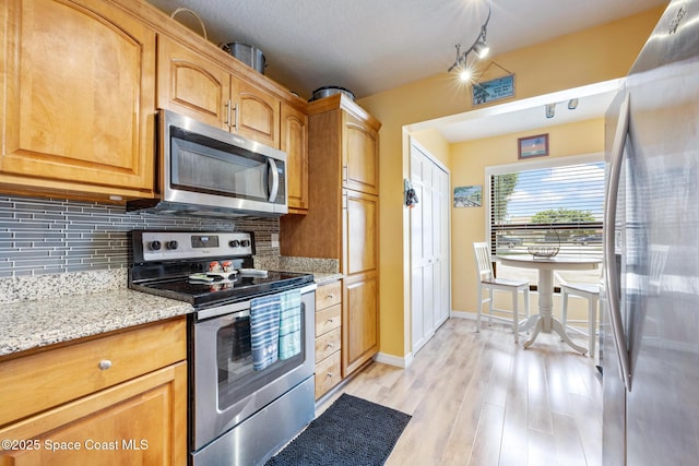 412 Sailfish Ave Unit 16, Cape Canaveral, FL 32920 - kitchen featuring stainless steel appliances, tasteful backsplash, light wood-style floors, light stone countertops, and baseboards
