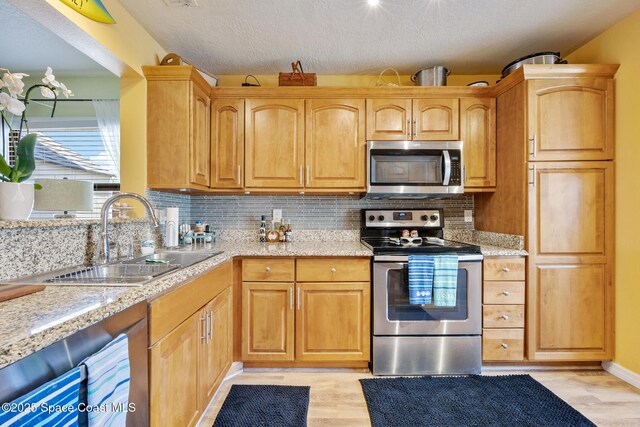 412 Sailfish Ave Unit 16, Cape Canaveral, FL 32920 - kitchen featuring stainless steel appliances, a sink, light wood-type flooring, tasteful backsplash, and light stone counters