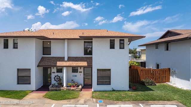 412 Sailfish Ave Unit 16, Cape Canaveral, FL 32920 - view of front of property featuring fence, stucco siding, a shingled roof, and uncovered parking