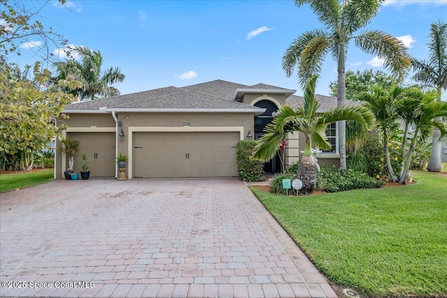 view of front of property with a front yard, stucco siding, decorative driveway, and a garage