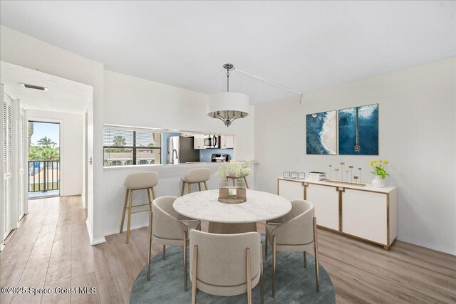 1950 Atlantic St Unit 223, Melbourne Beach, FL 32951 - dining area featuring light wood-type flooring, a chandelier, and baseboards