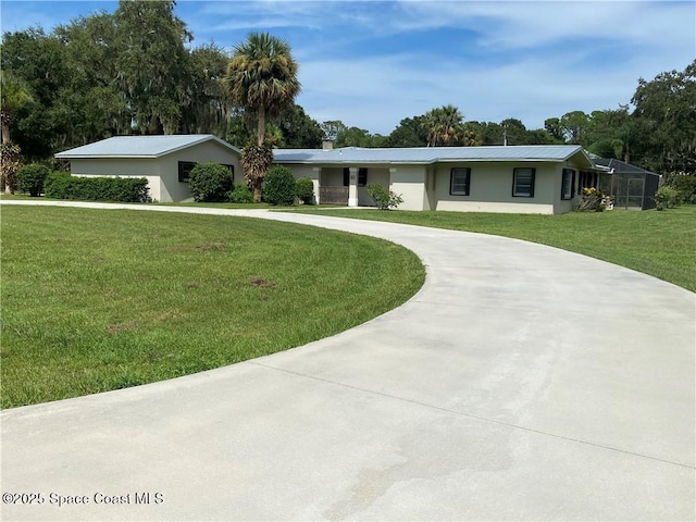 single story home featuring curved driveway, stucco siding, metal roof, and a front yard