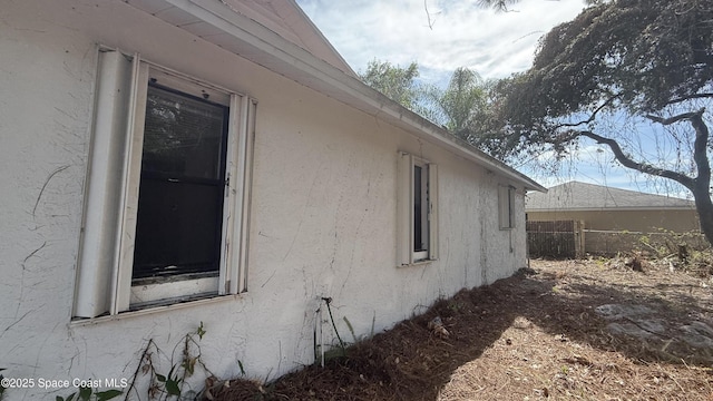 view of side of home with fence and stucco siding