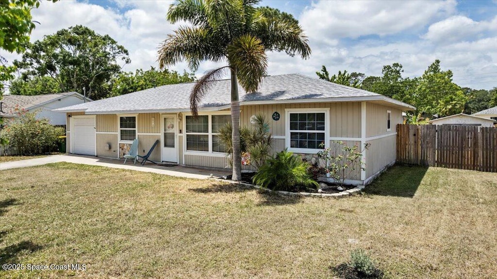 back of property with a yard, driveway, fence, and a garage