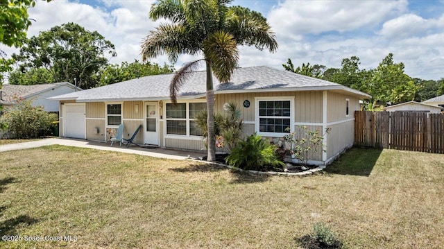 back of property with a yard, driveway, fence, and a garage