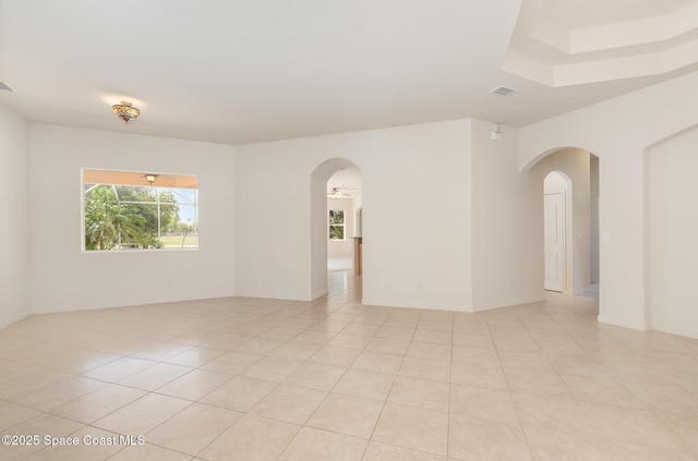 empty room with arched walkways and light tile patterned flooring