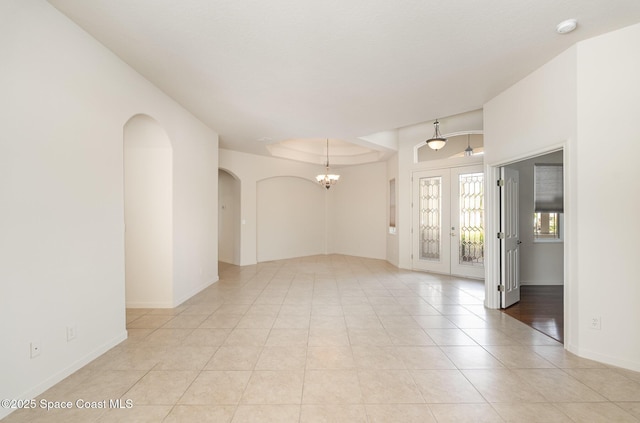unfurnished room with arched walkways, a chandelier, light tile patterned floors, french doors, and a smoke detector