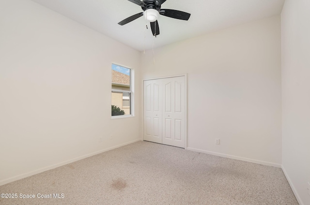 carpeted spare room with ceiling fan and baseboards