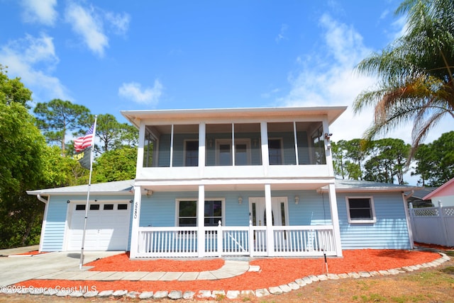 view of front of house featuring a porch, concrete driveway, a garage, and a sunroom