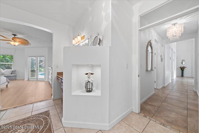 1085 Mercedes Dr, Merritt Island, FL 32952 - corridor featuring light tile patterned floors, a chandelier, and baseboards