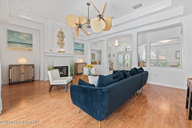 1085 Mercedes Dr, Merritt Island, FL 32952 - living room with a glass covered fireplace, light wood-type flooring, ornate columns, and baseboards