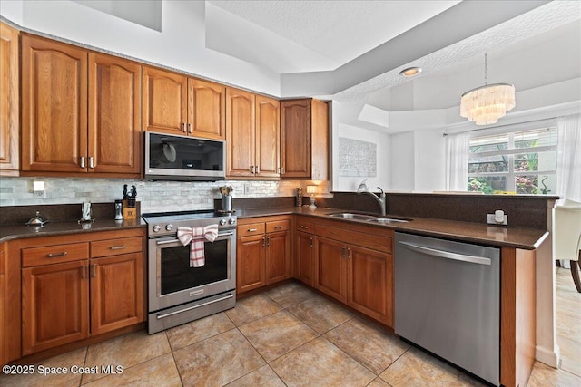 1085 Mercedes Dr, Merritt Island, FL 32952 - kitchen featuring appliances with stainless steel finishes, a sink, brown cabinets, a peninsula, and tasteful backsplash