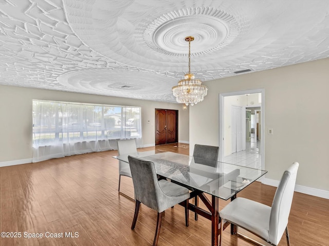 5118 Adams St, Hollywood, FL 33021 - dining space featuring a chandelier, light wood-style floors, and baseboards