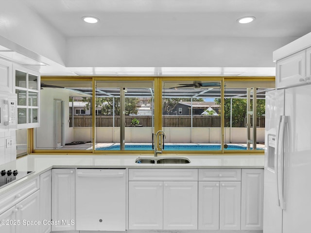 5118 Adams St, Hollywood, FL 33021 - kitchen featuring white appliances, a sink, white cabinetry, light countertops, and glass insert cabinets