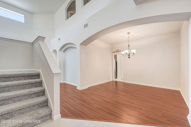3202 Arden Cir, Melbourne, FL 32934 - stairway with a chandelier, arched walkways, wood finished floors, baseboards, and a towering ceiling