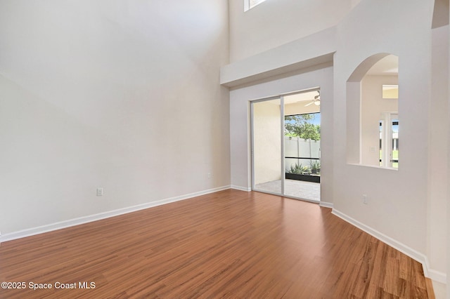3202 Arden Cir, Melbourne, FL 32934 - spare room with wood finished floors, arched walkways, baseboards, a ceiling fan, and a towering ceiling