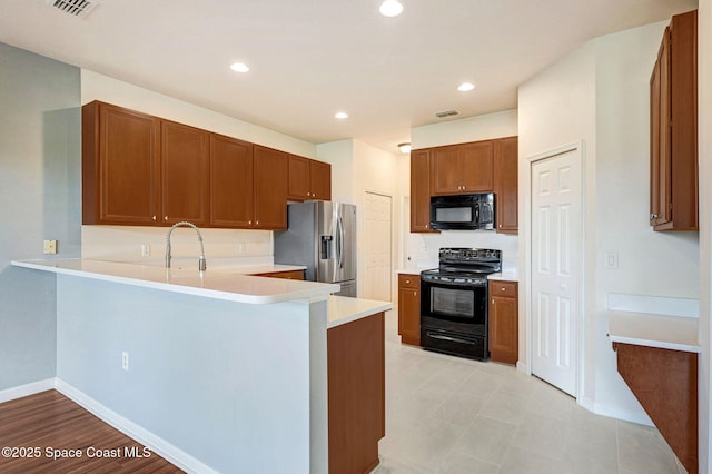 3202 Arden Cir, Melbourne, FL 32934 - kitchen featuring black appliances, a peninsula, light countertops, brown cabinetry, and recessed lighting