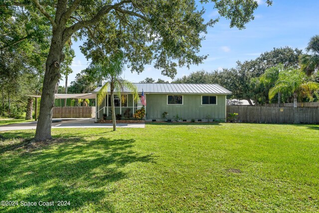 9633 Honeysuckle Dr, Sebastian, FL 32976 - view of front of house featuring metal roof, crawl space, fence, and a front yard