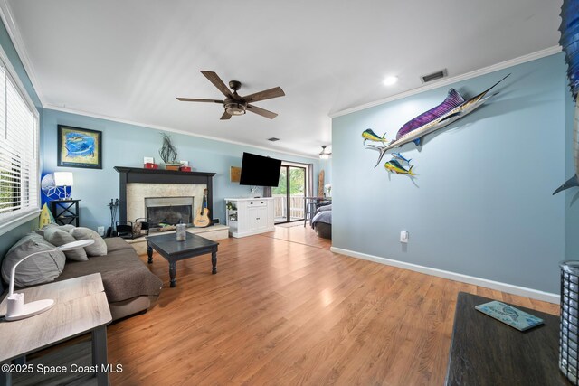 9633 Honeysuckle Dr, Sebastian, FL 32976 - living area featuring ornamental molding, a glass covered fireplace, ceiling fan, visible vents, and wood finished floors