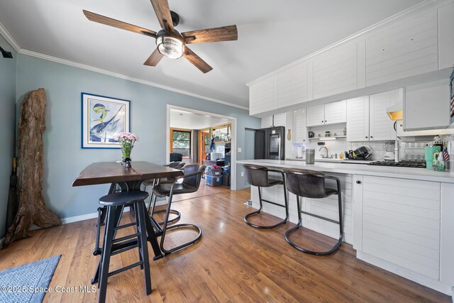 9633 Honeysuckle Dr, Sebastian, FL 32976 - kitchen with a peninsula, ornamental molding, a kitchen breakfast bar, ceiling fan, and white cabinetry