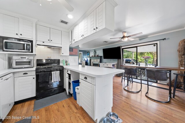 9633 Honeysuckle Dr, Sebastian, FL 32976 - kitchen with a peninsula, stainless steel microwave, a ceiling fan, and black range with gas stovetop