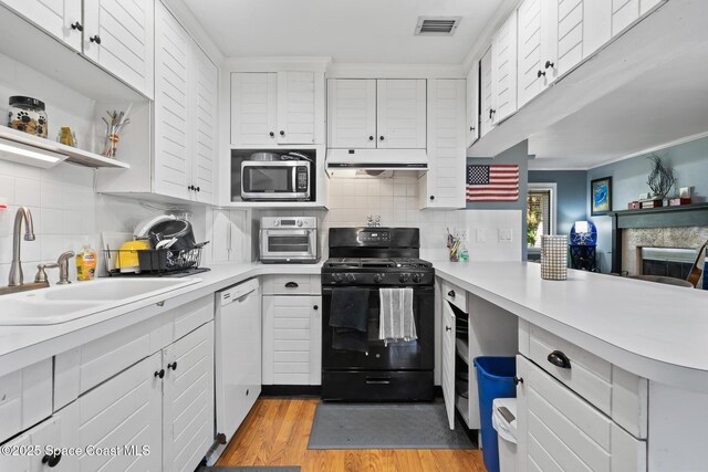 9633 Honeysuckle Dr, Sebastian, FL 32976 - kitchen featuring stainless steel microwave, a sink, dishwasher, under cabinet range hood, and black range with gas cooktop