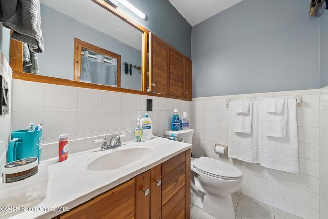 9633 Honeysuckle Dr, Sebastian, FL 32976 - bathroom featuring tile walls, toilet, wainscoting, tile patterned floors, and vanity