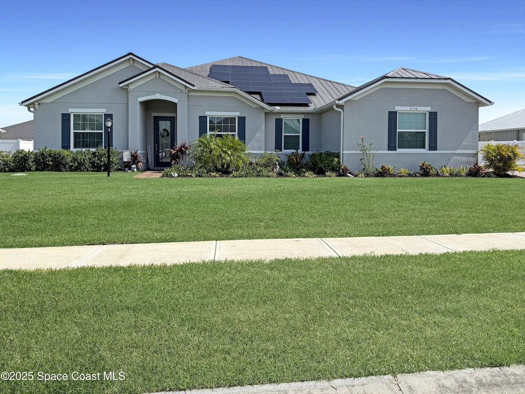 4190 Domain Ct, Melbourne, FL 32934 - ranch-style house featuring a standing seam roof, roof mounted solar panels, a front yard, and metal roof
