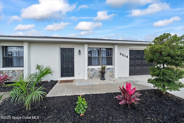 view of front of house featuring a garage, stucco siding, and stone siding