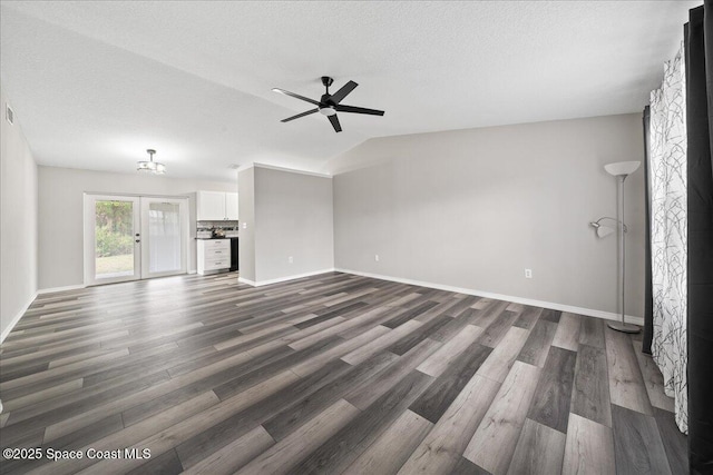 unfurnished living room with dark wood-style floors, ceiling fan, baseboards, lofted ceiling, and a textured ceiling
