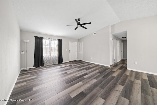 unfurnished living room with ceiling fan, vaulted ceiling, dark wood-type flooring, and baseboards