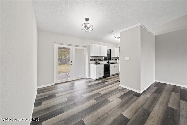 kitchen with black dishwasher, white cabinets, a sink, dark wood-style floors, and a textured ceiling