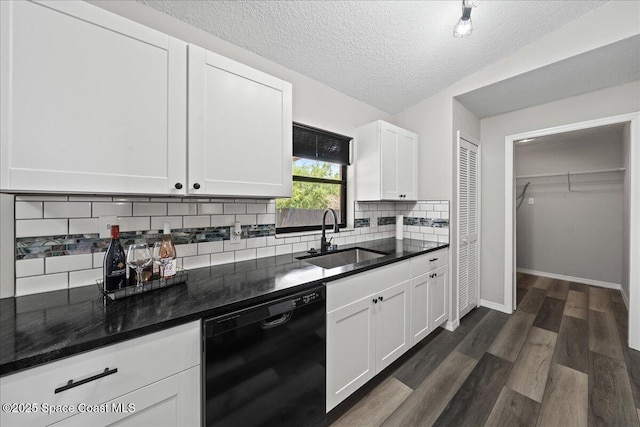 kitchen with black dishwasher, a sink, white cabinets, decorative backsplash, and dark wood-type flooring