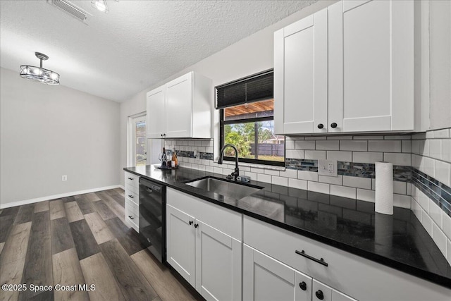 kitchen featuring a sink, dishwasher, dark wood finished floors, white cabinetry, and baseboards