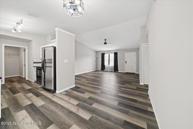 unfurnished living room with ceiling fan, dark wood finished floors, baseboards, a textured ceiling, and lofted ceiling