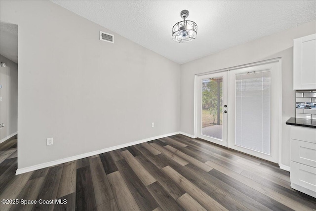 unfurnished dining area with french doors, dark wood-style flooring, a textured ceiling, baseboards, and lofted ceiling